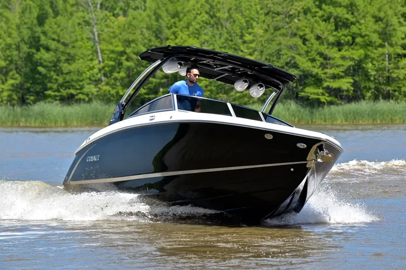 Slide: The Image of 2018 Cobalt R7 boat cruising on a lake with lush green trees in the background. - 6