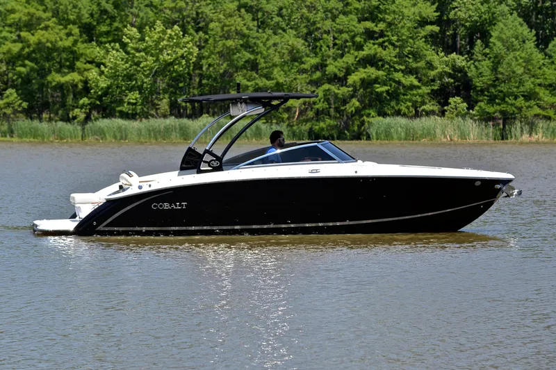 Slide: The Image of 2018 Cobalt R7 boat cruising on a calm lake with lush green trees. - 8