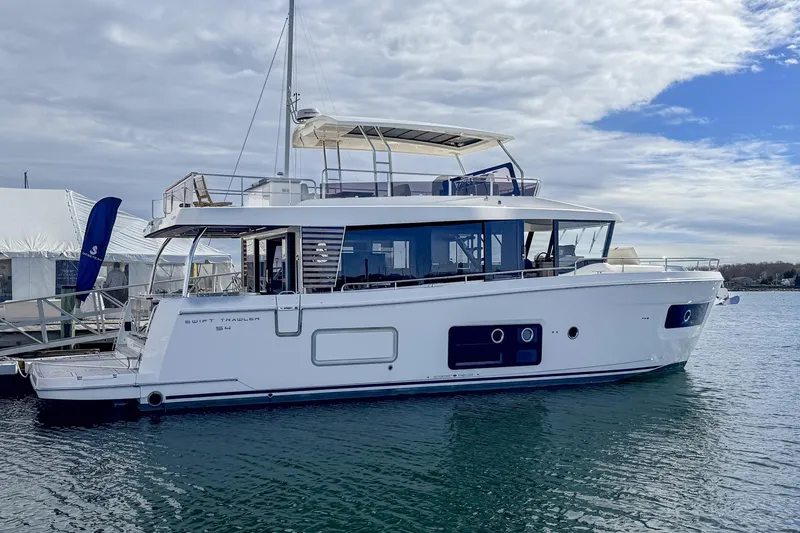 Slide: The Image of 2026 Beneteau Swift Trawler 54 yacht docked on a calm waterway. - 2