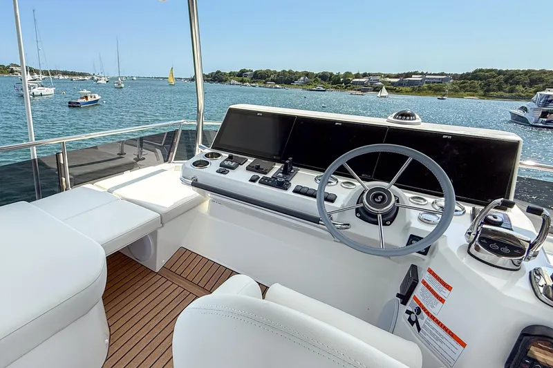 Slide: The Image of Flybridge of 2026 Beneteau Swift Trawler 54 with modern helm, overlooking serene waters. - 20