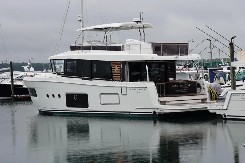 Slide: The Image of 2026 Beneteau Swift Trawler 54 docked in a marina, side view. - 31