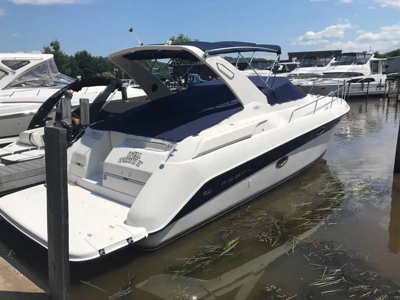 Slide: The Image of 1999 Regal 322 Commodore boat docked in a marina under a clear blue sky. - 1