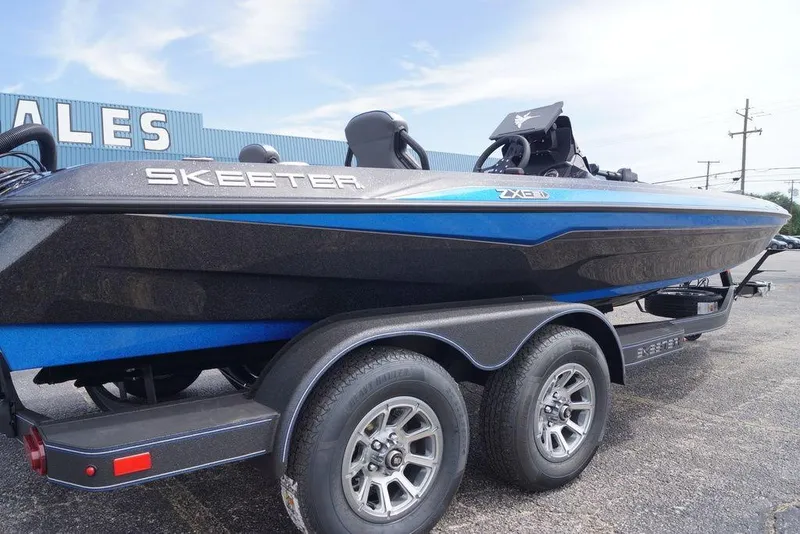 Slide: The Image of 2026 Skeeter ZXE21 boat on trailer, blue and black design, parked outdoors. - 5