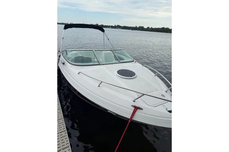 Slide: The Image of 2008 Regal 2250 Cuddy boat docked on calm water under a cloudy sky. - 14