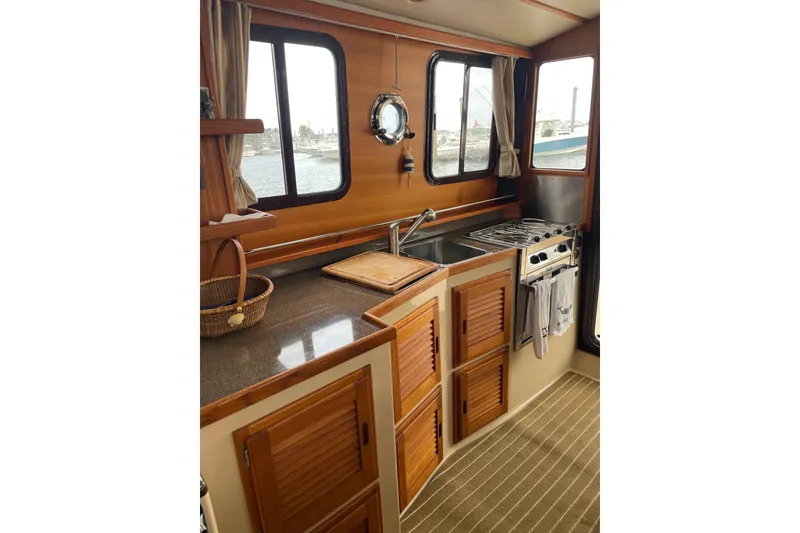 Slide: The Image of Cozy kitchen area in 2019 Ranger Tugs R-31 CB boat with wooden cabinets and windows. - 11
