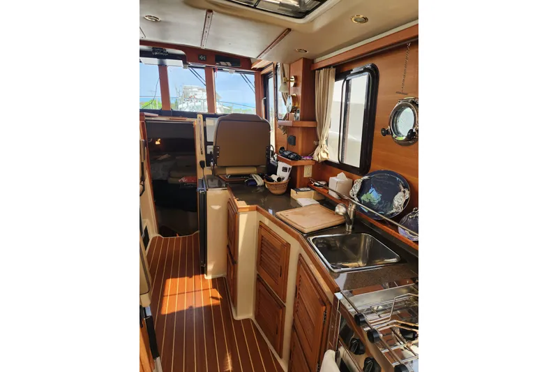 Slide: The Image of Interior of 2019 Ranger Tugs R-31 CB, featuring a well-equipped kitchen and helm station. - 12