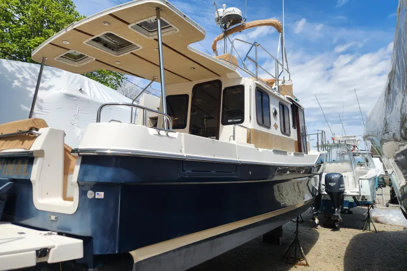 Slide: The Image of 2019 Ranger Tugs R-31 CB boat with blue hull, docked outdoors under a clear sky. - 6