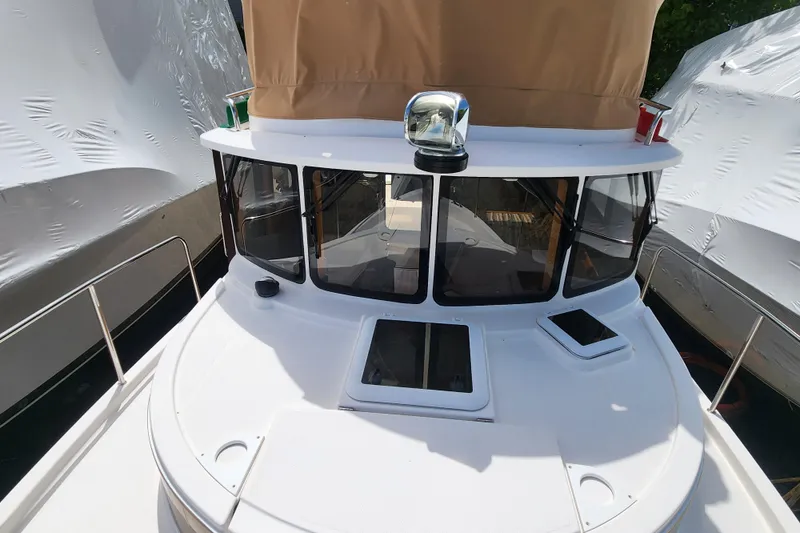 Slide: The Image of 2019 Ranger Tugs R-31 CB boat with tan canopy, docked between covered vessels. - 7