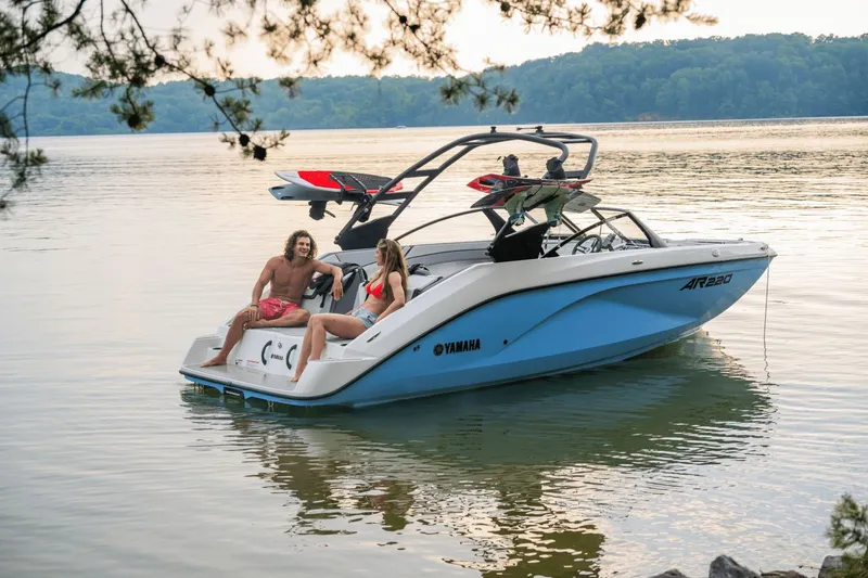 Slide: The Image of 2024 Yamaha AR220 boat on a serene lake with two people. - 3
