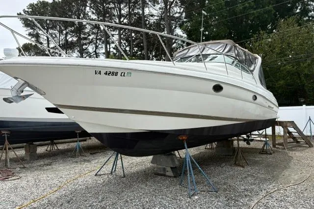 Slide: The Image of 2001 Wellcraft 3300 Martinique boat on stands, white hull, parked outdoors. - 2