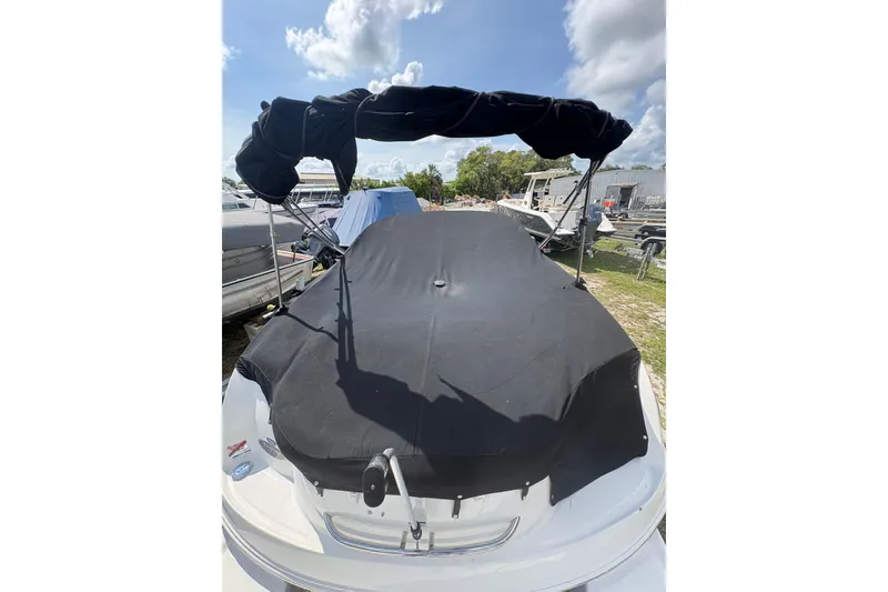 Slide: The Image of 2006 Chaparral Sunesta 236 boat with black cover and canopy, parked outdoors. - 1