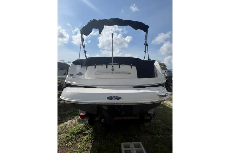Slide: The Image of 2006 Chaparral Sunesta 236 boat with black canopy, rear view under cloudy sky. - 3