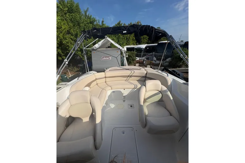 Slide: The Image of 2006 Chaparral Sunesta 236 boat interior with beige seating and canopy, parked outdoors. - 5