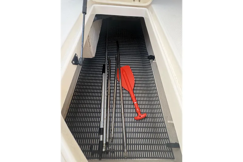 Slide: The Image of Storage compartment in 2006 Chaparral Sunesta 236 with fishing rods and red paddle. - 8