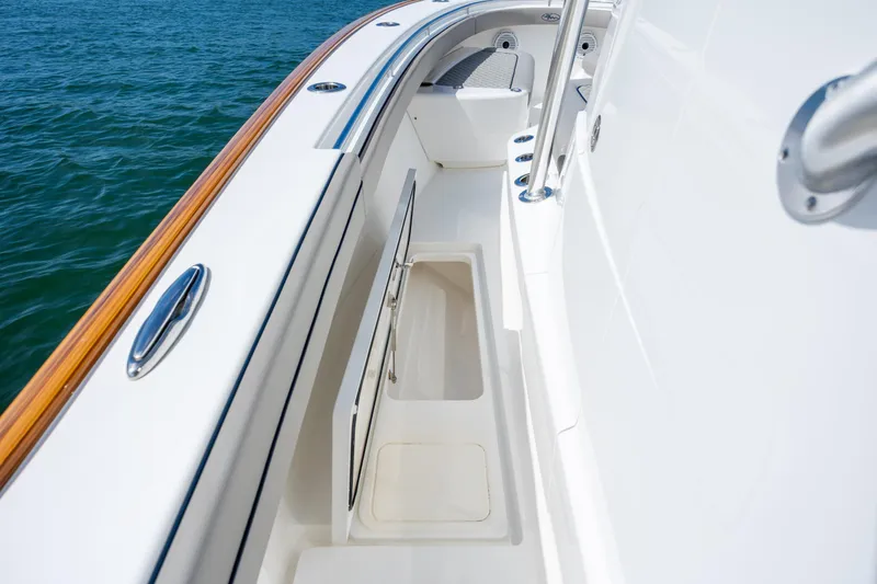 Slide: The Image of 2022 Valhalla Boatworks V-33 deck view with storage compartment, sleek design, and ocean backdrop. - 43