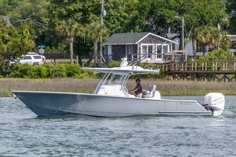 Slide: The Image of 2022 Valhalla Boatworks V-33 cruising on a scenic waterway near a coastal home. - 6
