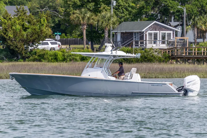 Slide: The Image of 2022 Valhalla Boatworks V-33 cruising on a scenic waterway near a coastal home. - 7