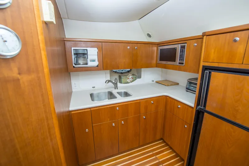 Slide: The Image of 2002 Tiara Yachts 4100 Open galley with wooden cabinets, sink, and appliances. - 20