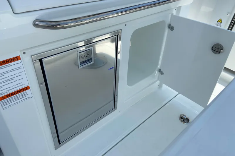 Slide: The Image of 2026 Jeanneau Leader 9.0 WA Series 2 boat storage compartment with open door and warning labels. - 13