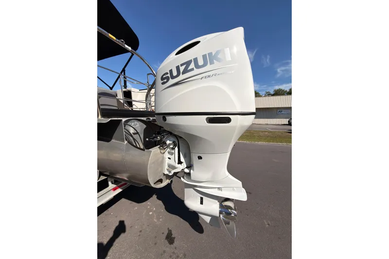Slide: The Image of 2021 Godfrey 2286 boat with Suzuki outboard motor, parked outdoors under clear blue sky. - 7