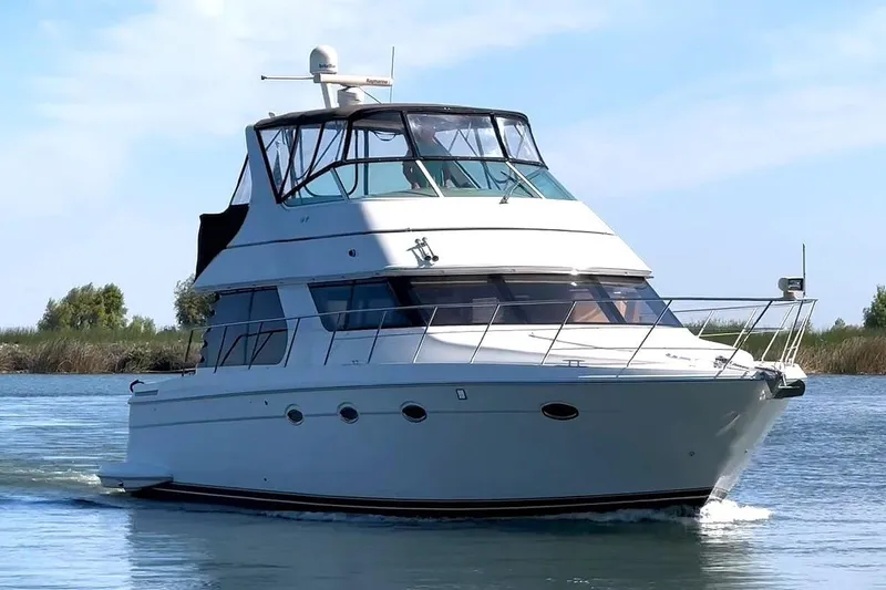 The Image of 2006 Carver 46 Voyager yacht cruising on a calm waterway under a clear sky. - 0