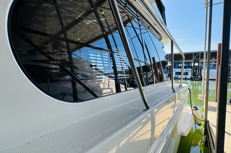 Slide: The Image of 2006 Carver 46 Voyager yacht docked, reflecting marina surroundings on its sleek windows. - 16