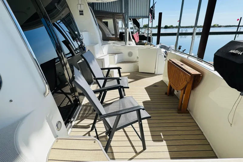Slide: The Image of 2006 Carver 46 Voyager yacht deck with chairs and table, overlooking serene water. - 23