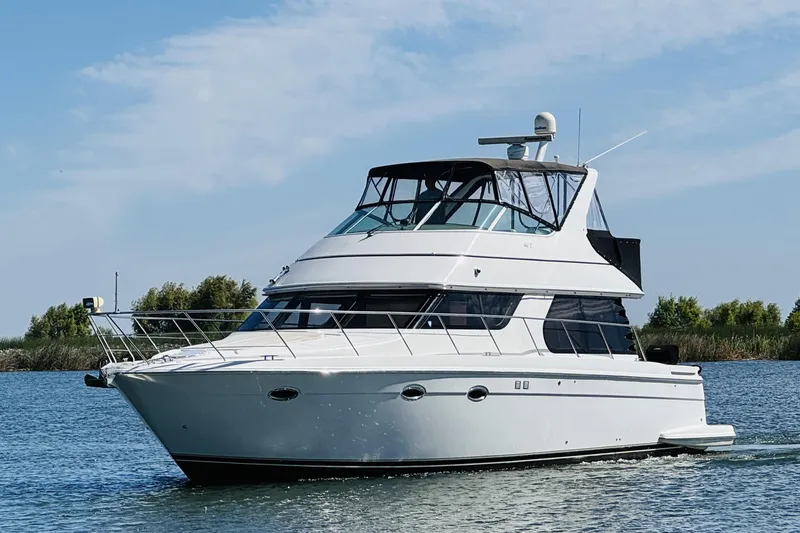 Slide: The Image of 2006 Carver 46 Voyager yacht cruising on a serene waterway under a clear sky. - 4