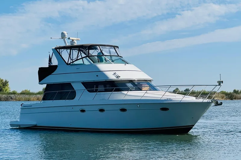 Slide: The Image of 2006 Carver 46 Voyager yacht on calm water under a clear blue sky. - 6