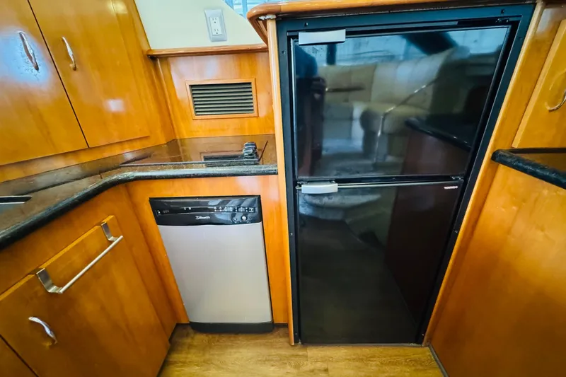 Slide: The Image of 2006 Carver 46 Voyager yacht kitchen with wood cabinetry, black countertops, and stainless steel appliances. - 64