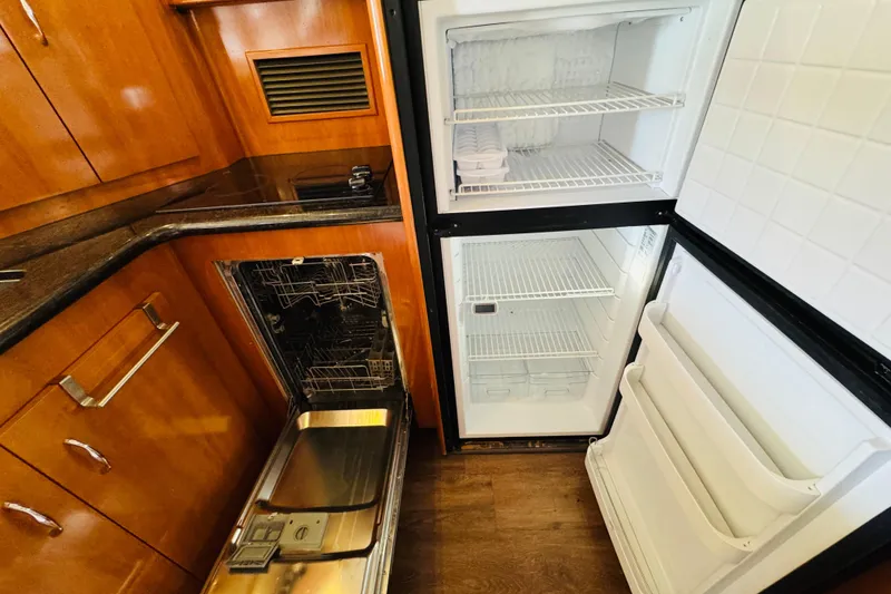 Slide: The Image of 2006 Carver 46 Voyager kitchen with open fridge and dishwasher, showcasing wooden cabinetry. - 65