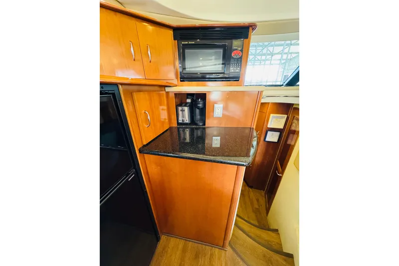 Slide: The Image of 2006 Carver 46 Voyager yacht kitchen with microwave, wooden cabinets, and black countertop. - 67