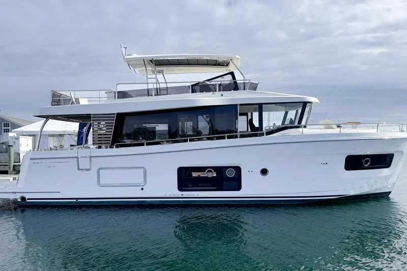 The Image of 2026 Beneteau Swift Trawler 54 yacht docked on calm water under cloudy sky. - 1