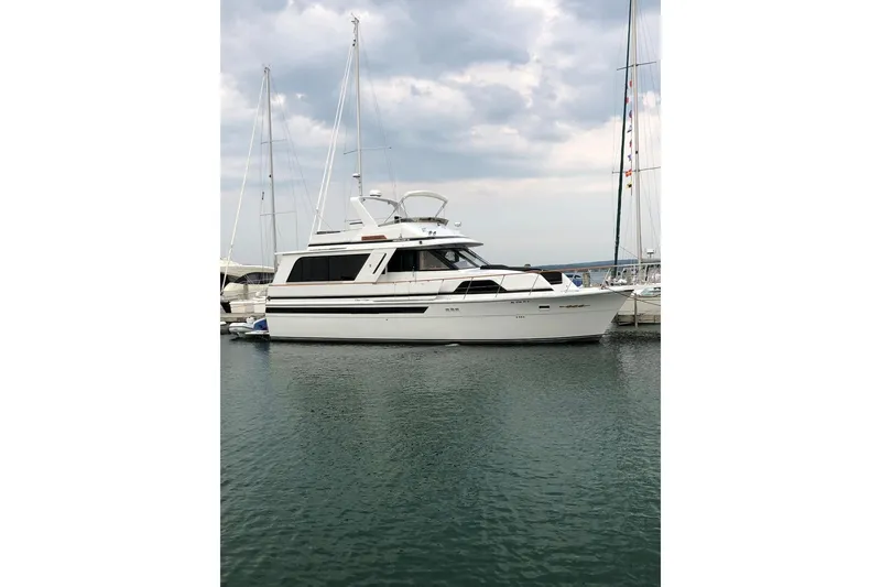 The Image of 1988 Chris-Craft 501 Motor Yacht docked in a marina under cloudy skies. - 1