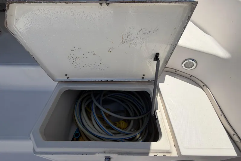 Slide: The Image of Open storage compartment on 1994 Grady-White Sailfish 272 boat, containing coiled hoses. - 23