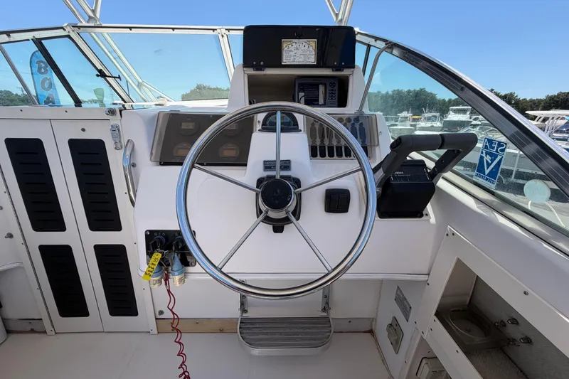 Slide: The Image of 1994 Grady-White Sailfish 272 helm with steering wheel and controls, docked in marina. - 28