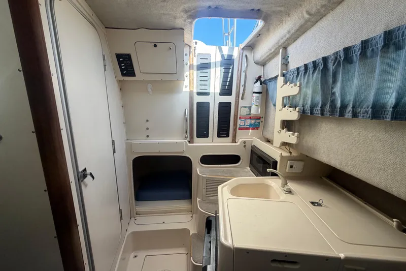 Slide: The Image of Interior of a 1994 Grady-White Sailfish 272 boat, featuring a compact kitchenette and storage. - 52