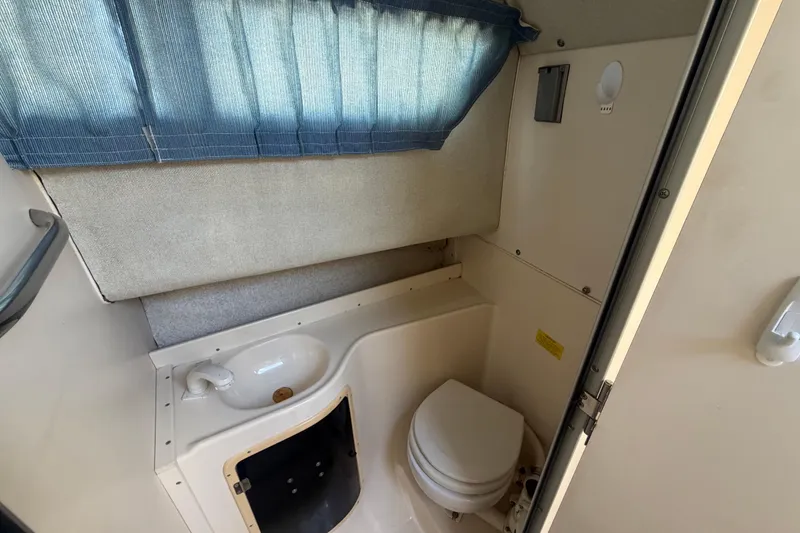 Slide: The Image of 1994 Grady-White Sailfish 272 boat bathroom with sink, toilet, and blue curtain. - 64
