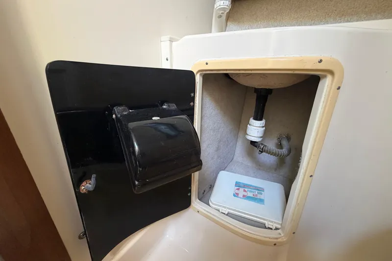 Slide: The Image of 1994 Grady-White Sailfish 272 storage compartment with first aid kit and plumbing. - 66
