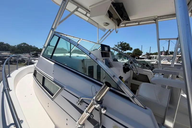 Slide: The Image of 1994 Grady-White Sailfish 272 boat cockpit with steering wheel and seating, docked outdoors. - 83