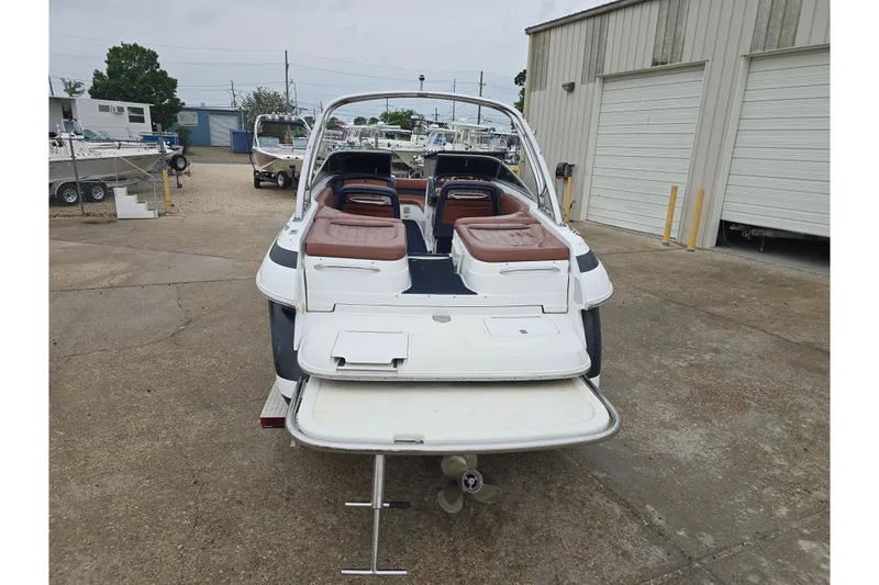 Slide: The Image of 2003 Cobalt 262 boat with open deck and brown seating, parked near industrial buildings. - 2