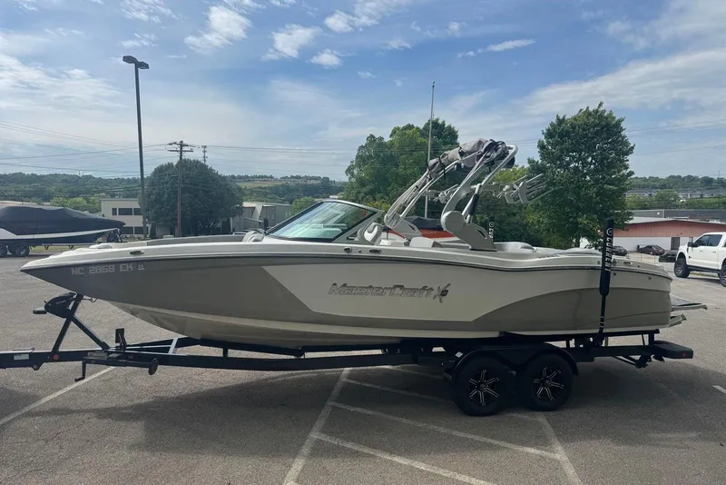 Slide: The Image of 2017 MasterCraft X26 boat on trailer in parking lot under cloudy sky. - 2