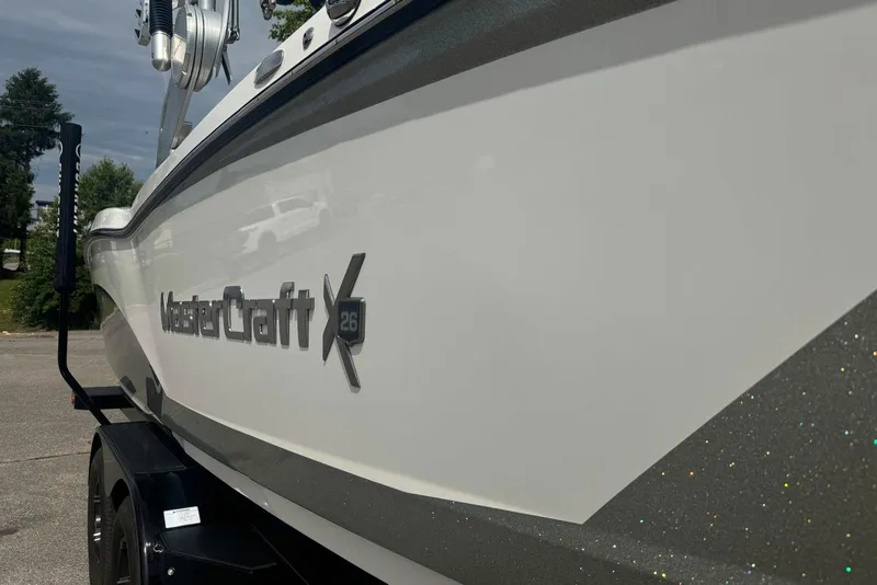 Slide: The Image of 2017 MasterCraft X26 boat side view with logo, parked outdoors. - 3