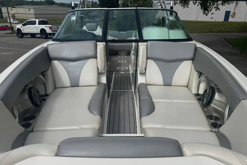 Slide: The Image of 2017 MasterCraft X26 boat interior with gray and white seating, cup holders, and speakers. - 6