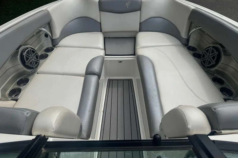 Slide: The Image of 2017 MasterCraft X26 boat interior with white and gray seating, cup holders, and speakers. - 8