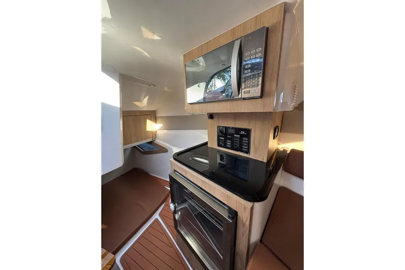 Slide: The Image of Interior of 2025 NX Boats NX290 Exclusive, featuring modern kitchen appliances and wood finishes. - 25