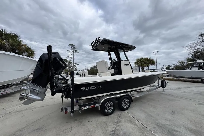 Slide: The Image of 2026 ShearWater 260 Carolina Flare boat on trailer, parked outdoors under cloudy sky. - 10