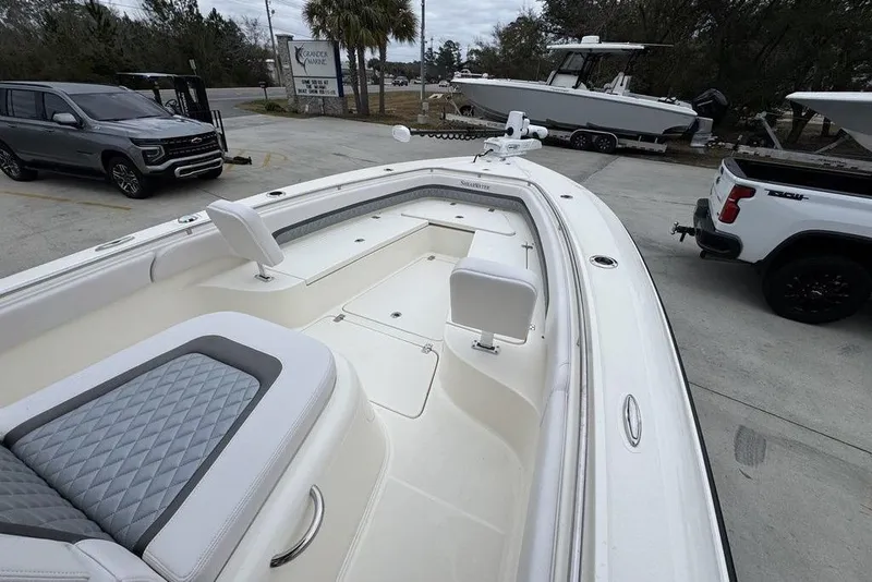 Slide: The Image of 2026 ShearWater 260 Carolina Flare boat with spacious seating, parked near vehicles. - 17