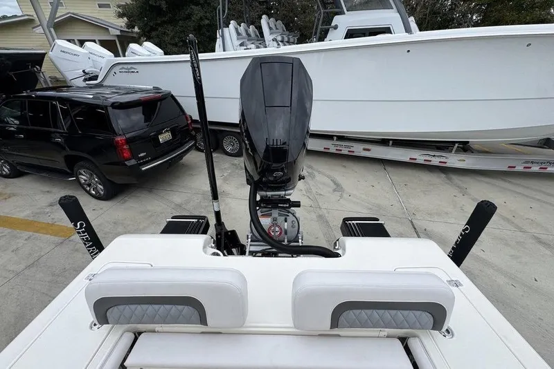 Slide: The Image of 2026 ShearWater 260 Carolina Flare boat with outboard motor, parked near SUV and trailer. - 38