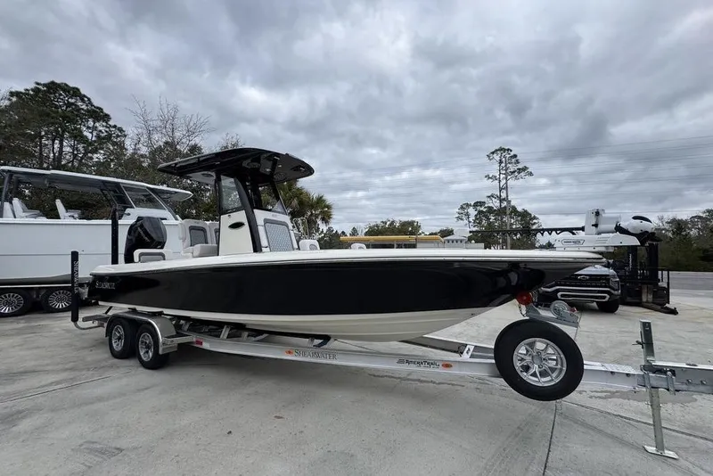 Slide: The Image of 2026 ShearWater 260 Carolina Flare boat on trailer, parked outdoors under cloudy sky. - 7
